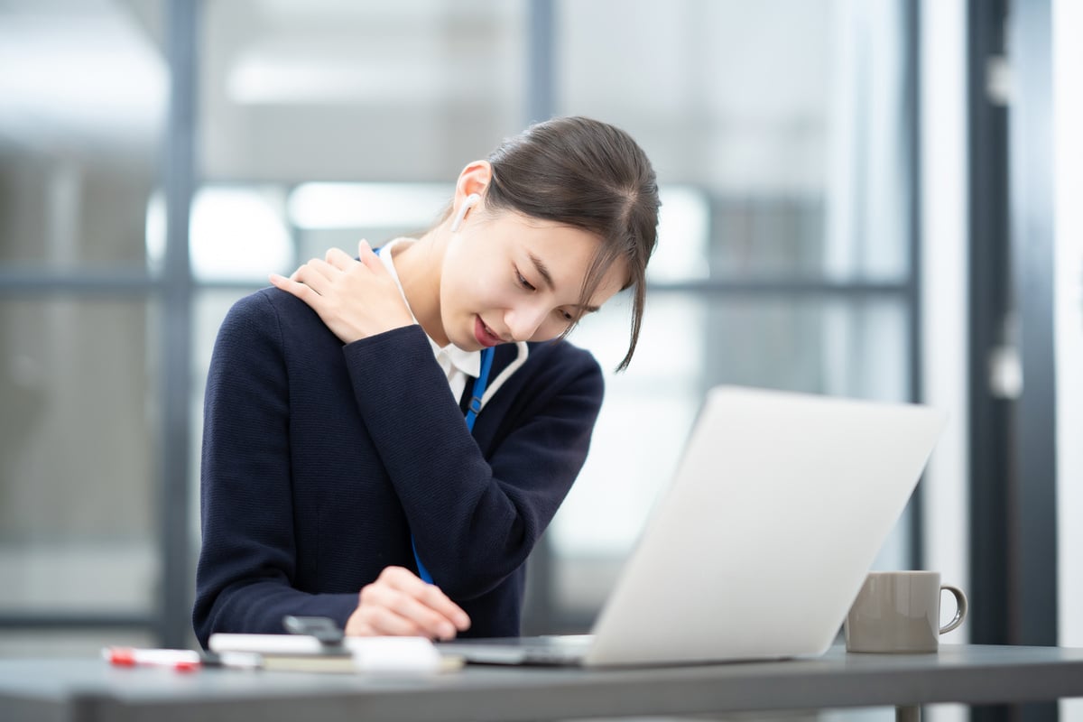 Young woman suffering from stiff shoulders at desk work